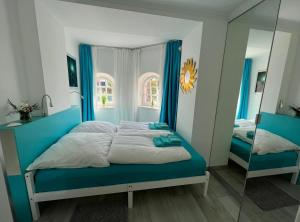 ein Schlafzimmer mit einem blauen Bett und einem Spiegel in der Unterkunft Wohnen an der Havel in Schwielowsee