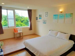 a bedroom with a large white bed and a window at Julie's Garden in Hengchun South Gate