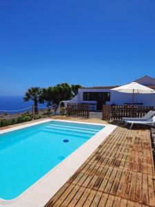 a swimming pool with a wooden deck and an umbrella at Casa Los Llanos in Playa de Santiago