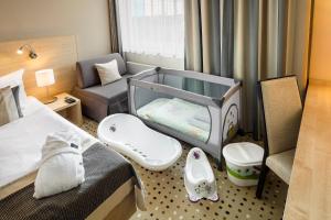 a bedroom with a baby crib and a couch at Aquapalace Hotel Prague in Čestlice