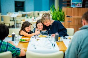 a woman and two girls sitting at a table eating food at Aquapalace Hotel Prague in Čestlice