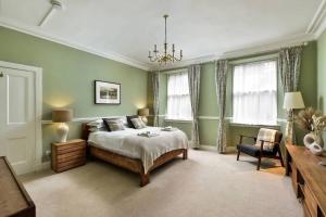 ein Schlafzimmer mit grünen Wänden, einem Bett und einem Kronleuchter in der Unterkunft 8b Howard Place in St Andrews