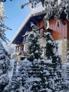 una cabaña de madera en invierno con nieve en las escaleras en Vikendica Klara, en Jablanica