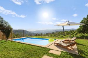 a swimming pool with an umbrella and chairs and a table at Casa do Vitó in Couto