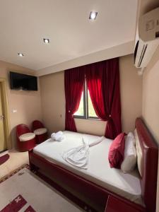 1 dormitorio con 1 cama y una ventana con cortinas rojas en Hotel Selfo, en Gjirokastra