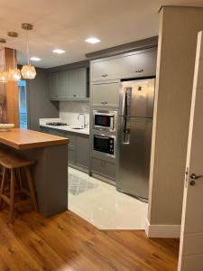 uma cozinha com electrodomésticos em aço inoxidável e piso em madeira em Apartamento novinho na Borges de medeiros- CENTRO em Gramado