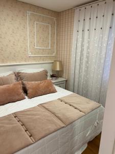um quarto com uma grande cama branca e uma janela em Apartamento novinho na Borges de medeiros- CENTRO em Gramado