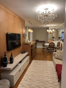 uma sala de estar com televisão e uma sala de jantar em Apartamento novinho na Borges de medeiros- CENTRO em Gramado
