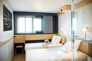 ル・メニル・アムロにあるノマド パリ ロワシー CDGのベッド2台と窓が備わるホテルルームです。
