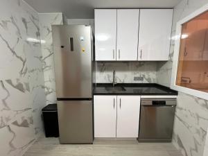 uma cozinha com armários brancos e um frigorífico em Apartamento Ninfa - Wifi, Piscina, A/C, Lavadora, silla de ruedas bienvenidas em Fuengirola