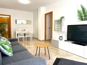 uma sala de estar com um sofá e uma televisão de ecrã plano em Apartamento Ninfa - Wifi, Piscina, A/C, Lavadora, silla de ruedas bienvenidas em Fuengirola
