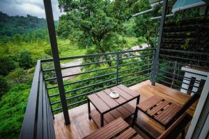 un balcón con una mesa de madera y sillas. en Misty Range Resorts en Maraiyūr