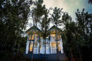 una casa blanca con árboles delante de ella en Misty Range Resorts en Maraiyūr