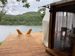 2 sillas sentadas en una terraza de madera junto a un lago en Reserva La Mision Mocona - Solo Adultos en Saltos del Moconá