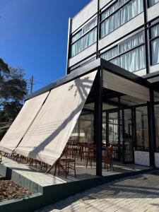 a building with awning outside of it with tables and chairs at JaguatiricaCoffee Hospitality in Monte Verde