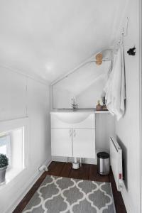 Baño blanco con lavabo y alfombra en Charming cottage outside Rattvik, en Vikarbyn