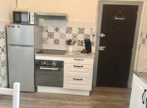 a small kitchen with a refrigerator and a microwave at Charmant T2 proche vieille ville in Montluçon