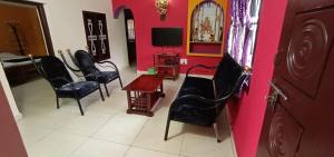a room with black chairs and a pink wall at Coorg girinivas homestay 102 in Madikeri