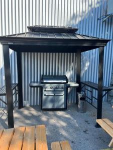 a barbecue under a picnic table with two benches at Wego Hotel in Bulle