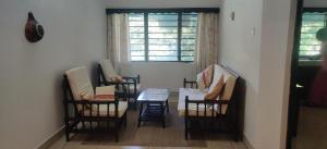 a room with three chairs and a table and a window at Bluebell Apartments in Diani Beach