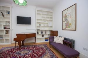 ein Wohnzimmer mit einem Klavier und einer lila Couch in der Unterkunft Pass the Keys Artistic and Stylish 2 Bedroom Flat in City Centre in Glasgow