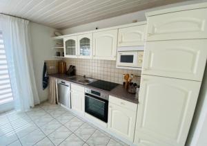 a kitchen with white cabinets and a white refrigerator at Seeglück22 in Reichenau