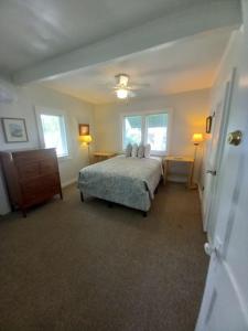 a bedroom with a bed and a dresser and two windows at Stegbone's Fish Camp and Resort in Satsuma