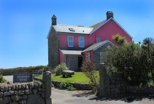 a red house with a sign in front of it at Sennen Rise in Sennen Cove