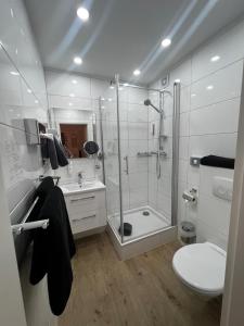 a white bathroom with a shower and a toilet at Hotel Granus in Aachen