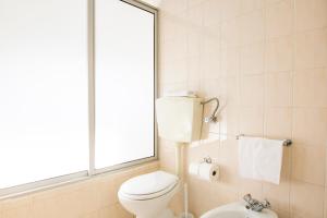 a bathroom with a toilet and a window at Dona Amélia Hotel by RIDAN Hotels in Fátima