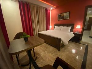 a hotel room with a bed and a table at AK Hotel & Suites in Murree