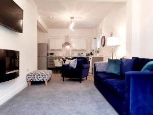 a living room with a blue couch and a kitchen at No's 7 and 8 Llewelyn Apartments in Llanberis