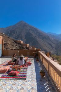 two people sitting on a balcony with a view of a mountain at Amazigh Family Riad in Imlil