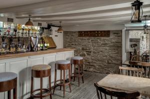 um bar com bancos de madeira e uma parede de tijolos em The Olde Malthouse Inn em Tintagel