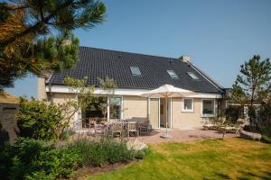 a house with an umbrella and chairs in the yard at Haus Janus 1 - Wohnung 1 in Norderney