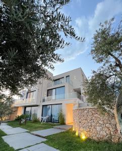 a white house with a stone wall and trees at Le Rêve Boutique Hotel in Dhërmi