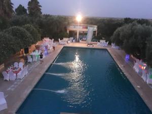 ein Pool mit weißen Stühlen und ein Gebäude in der Unterkunft Hotel complex europe in Guercif