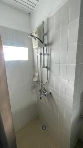 een douche in een wit betegelde badkamer bij Le coquillage in Trou aux Biches
