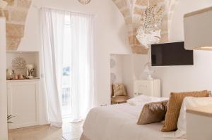 a white bedroom with a bed and a large window at Apulia Charming Suites - Casa Rossa Suite Perla e Suite Corallo in Savelletri di Fasano