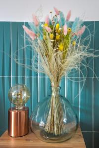 Un jarrón de cristal con flores al lado de un reloj. en Le Saint Charles, en Marsella