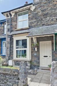 a stone house with a white door and windows at Bumble Choo Cottage - Windermere, Lake District in Windermere