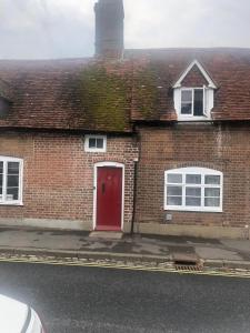 a brick house with a red door on a street at Double Room in Character Cottage With Parking, Beaulieu, New Forest in Beaulieu