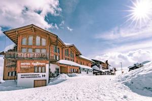 a building in the snow with the sun behind it at Hotel Eggishorn in Fiesch