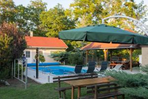 a green umbrella and a table and chairs by a pool at Motel Hummel in Pér