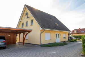 una casa gialla con tetto di gamberetti e vialetto di Maisonette-Ferienwohnung Karla a Ostseebad Karlshagen