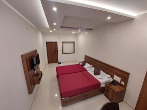 sypialnia z czerwonym łóżkiem i telewizorem w obiekcie FOUR SQUARE COMFORTS w mieście Manipala