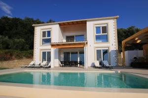 a villa with a swimming pool in front of a house at Sunset Sea View Villa 8 in Afionas