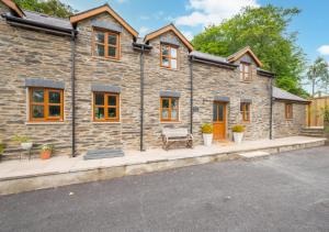 una casa de piedra con un banco delante en Hafod y Llwynog en Cross Inn