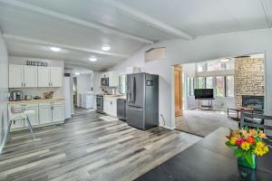 a large kitchen with white cabinets and a refrigerator at 2 Mi to Rainbow Lake Woodsy Retreat with Deck! in Pinetop-Lakeside