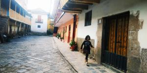 a woman walking down a street in an alley at Anais y Nicolas Hostel in Cusco